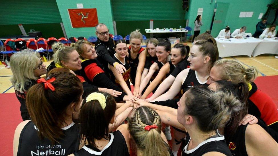 The Isle of Man team in a huddle with hands in the middle