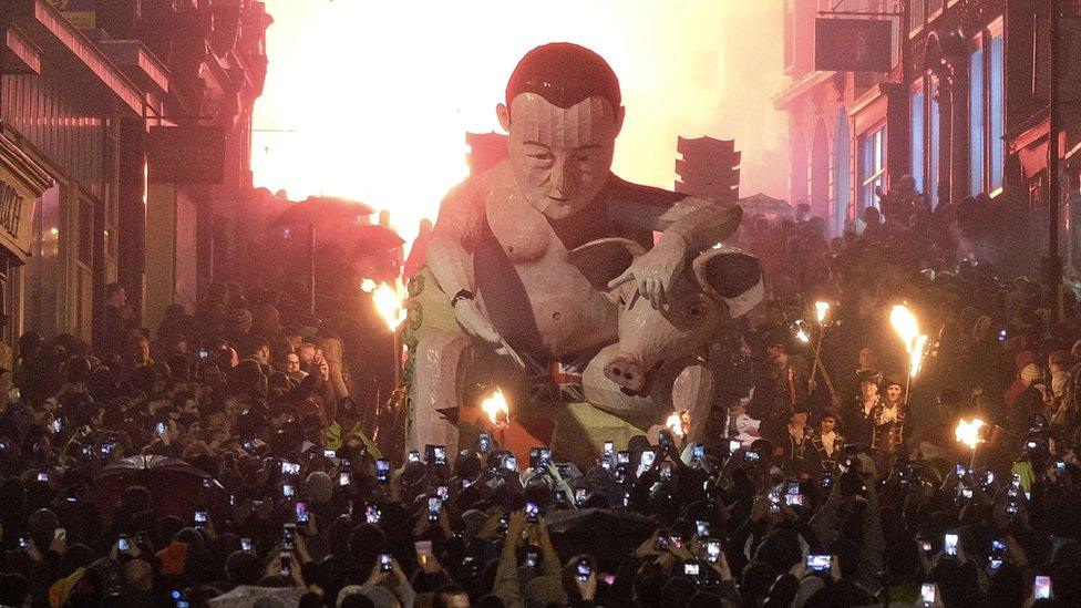 A crowd takes photos of the David Cameron effigy as it is paraded through Lewes