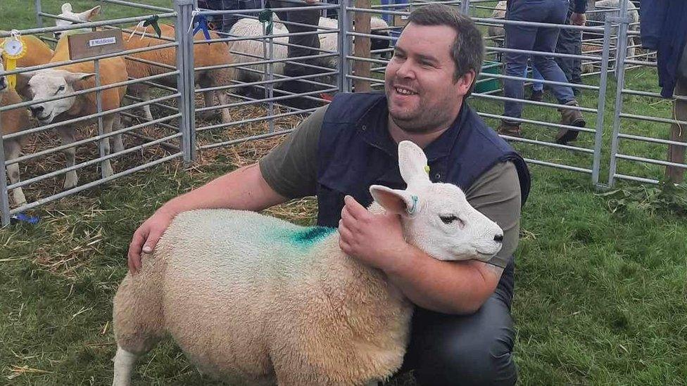 Richard Sunter holding a sheep in a pen