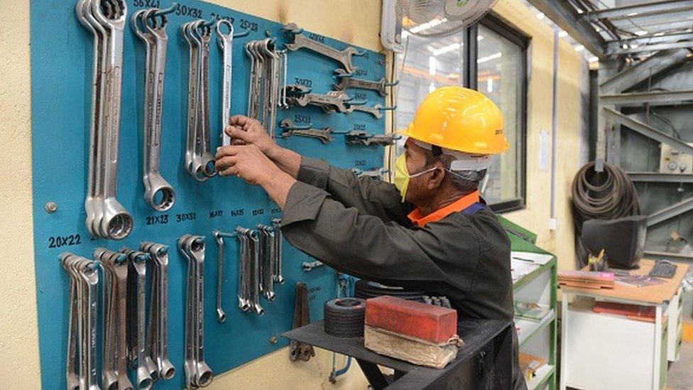 An Indian worker selects tools at a heavy fabrication manufacturing factory in Vasna Buzarg village