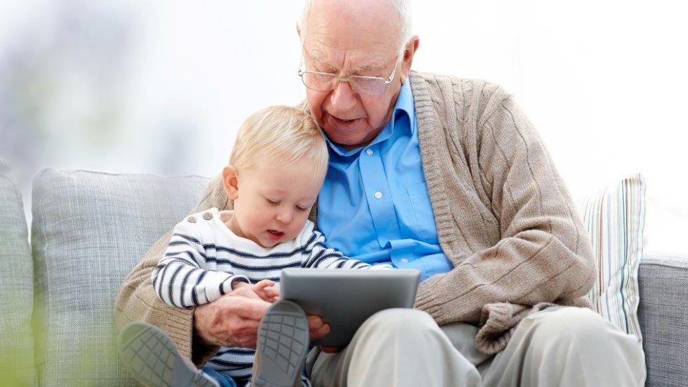 Old person looking at ipad with young person