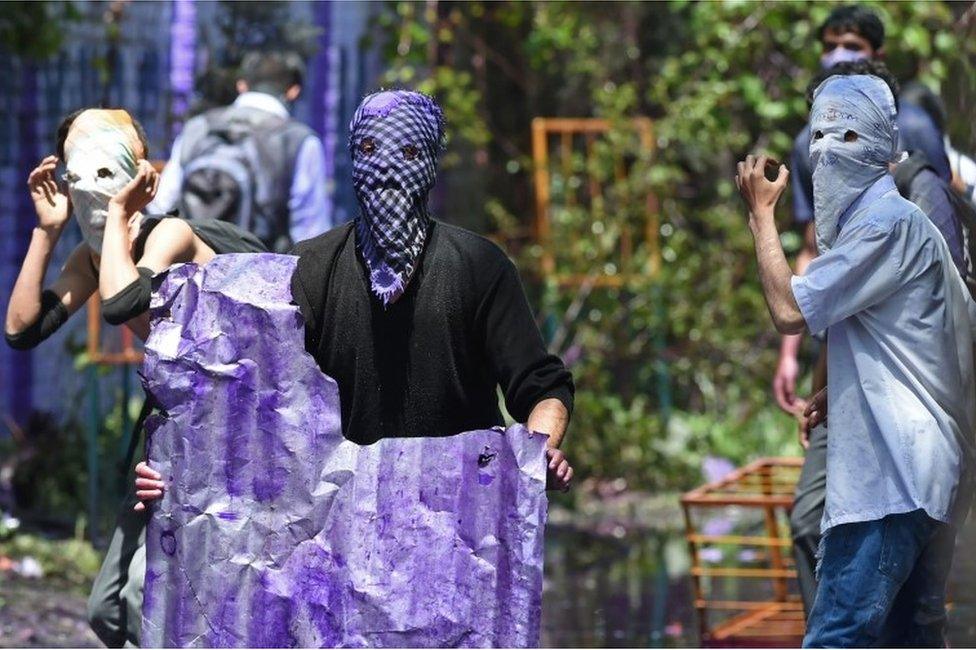 Kashmiri students wearing face masks look towards Indian government forces during clashes in central Srinagar"s Lal Chowk on April 24, 2017.