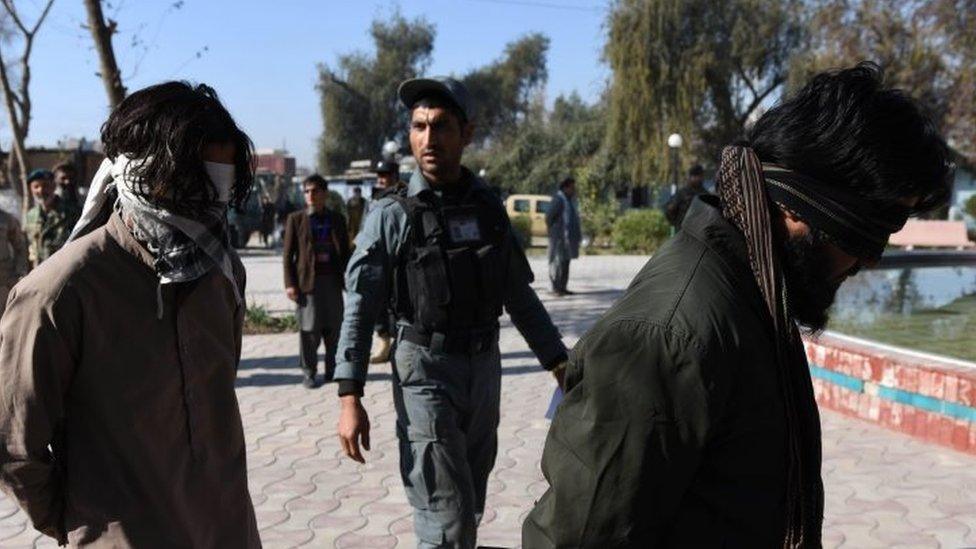 Members of the Afghan security services escort two alleged members of the group calling themselves Islamic State in the Bahsood district of Nangarhar province (20 January 2016)