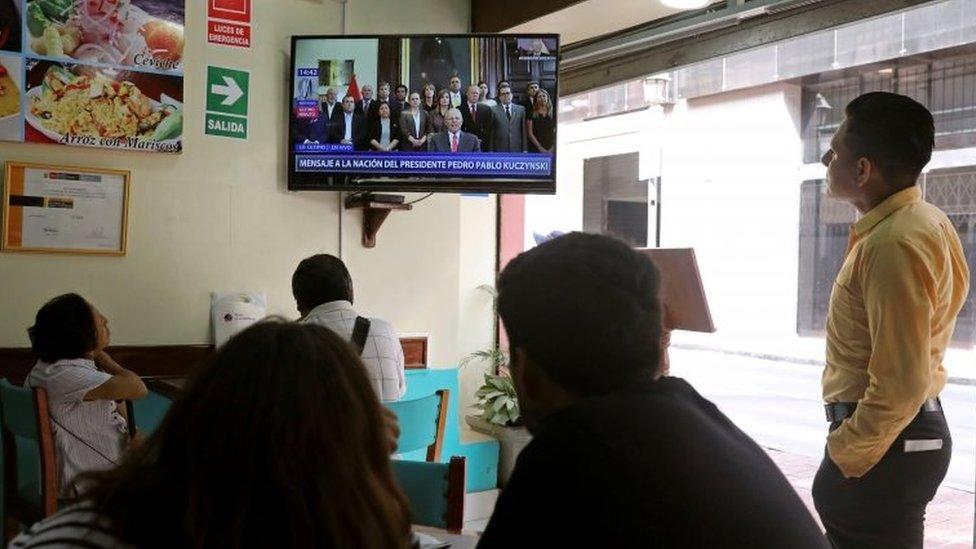 People look on as Peru's President Pedro Pablo Kuczynski addresses the nation as he resigns in Lima, Peru, March 21, 2018.