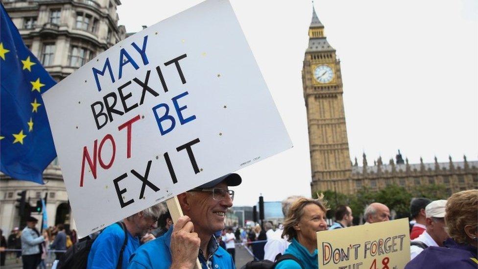 A man with a placard bearing a pro-Europe slogan "may Brexit not be exit" marches into Parliament Square in central London.