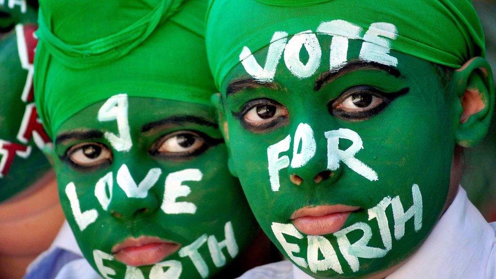 Indian students wearing green face paint with white writing