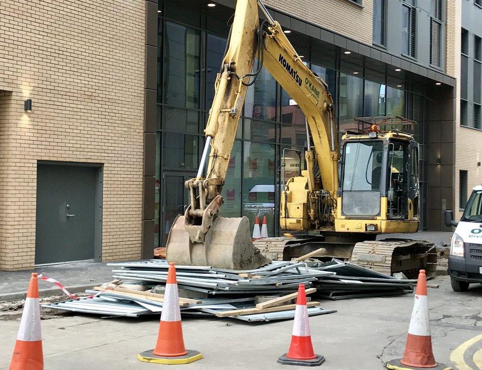 Digger holding down metal fence