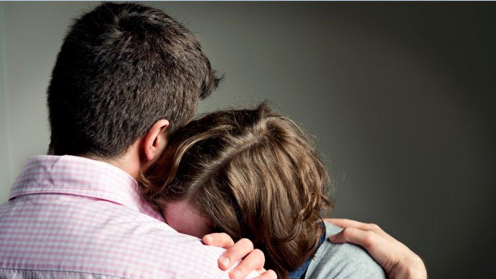 Stock image of two people hugging in sadness