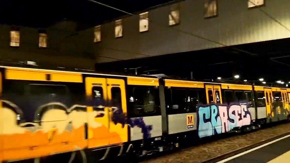 Large letters spelling CRASEE spray painted on to the side of a yellow Metro carriage