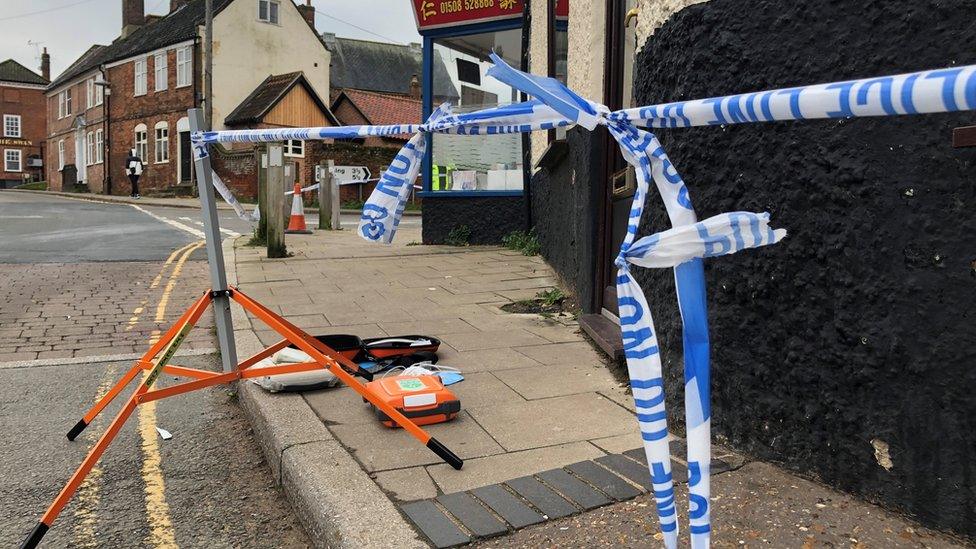 Police tape and defibrillator kit on the pavement in Bridge Street, Loddon.