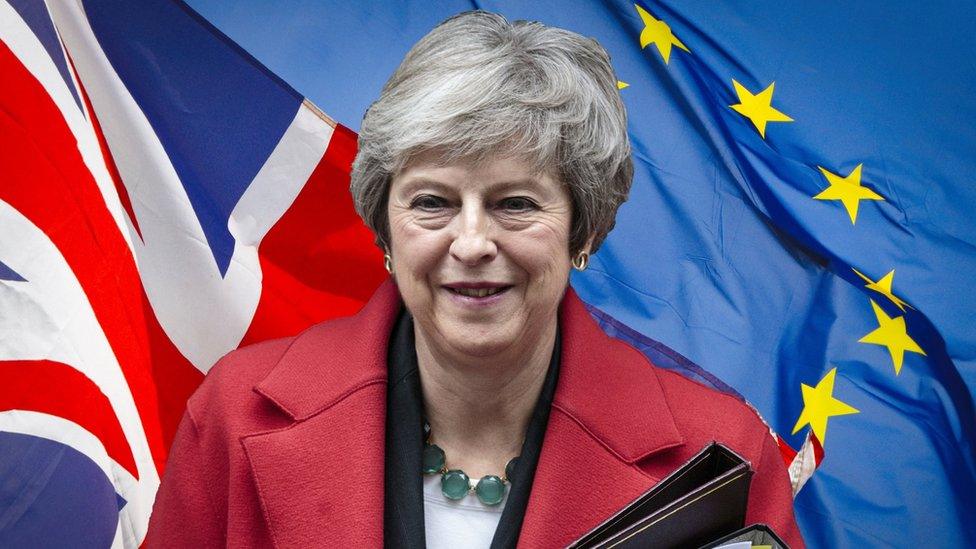 Theresa May in front of EU and UK flags.