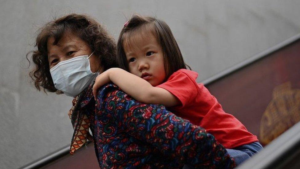 A girl rides on the back of a woman down an escalator at a shopping centre on International Children's Day in Beijing