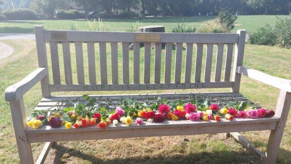 A bench with flowers laid out on it