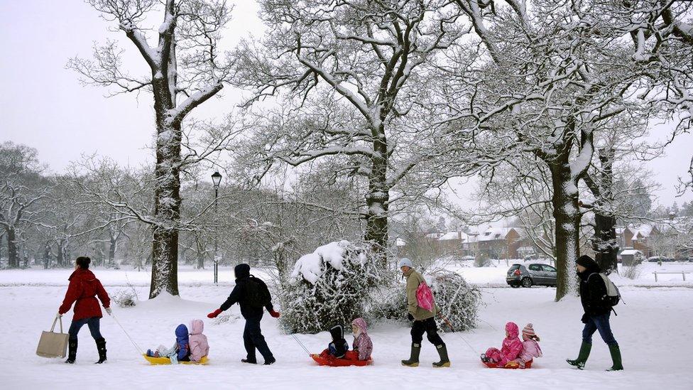 Adults pulling children on sledges