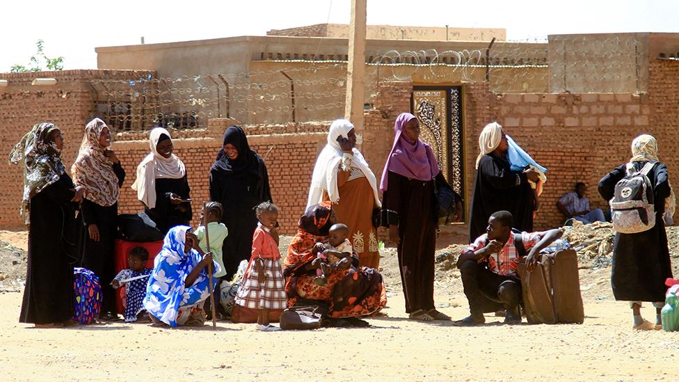 People fleeing street battles between the forces of two rival Sudanese generals, wait with their belongings along a road in the southern part of Khartoum, on April 21, 2023