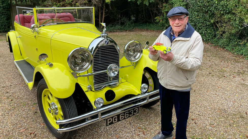 Malcolm Stern standing in front of a classic car, holding a 3D printed version of the car