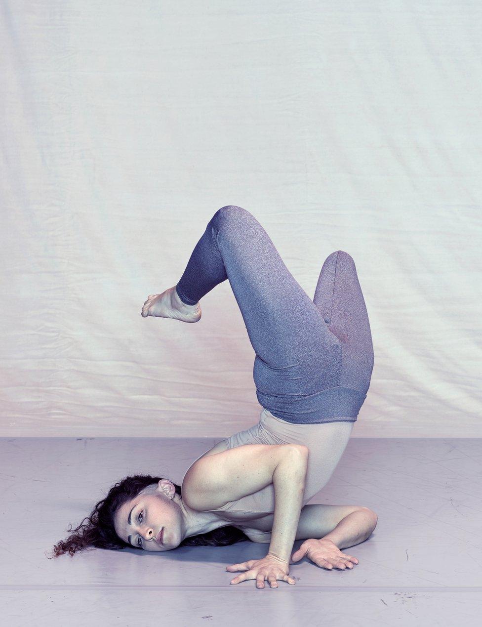 A dancer poses in front of a plain backdrop