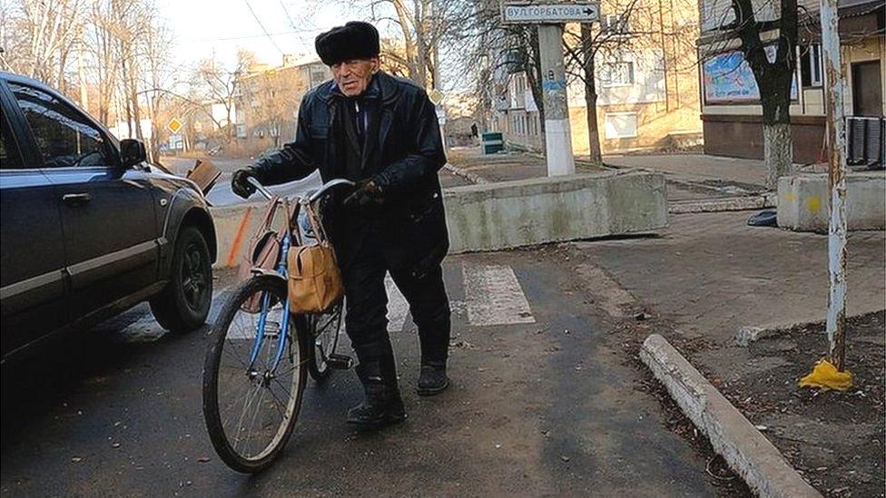 Older man pushes bicycle on street in Bakhmut