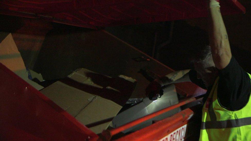 Driver Barry rummages through cardboard in a commercial recycling bin to check for rough sleepers