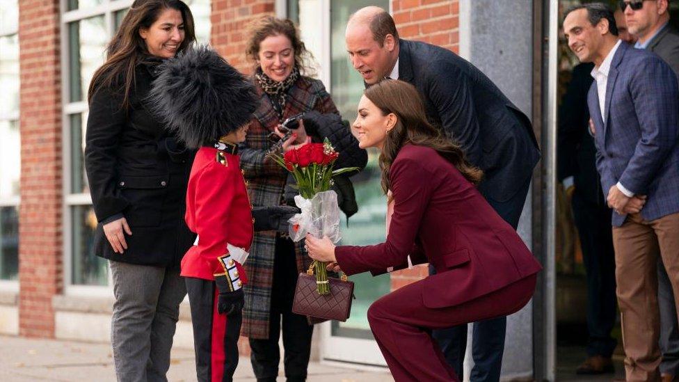 The Prince and Princess of Wales are presented with flowers by Henry Dynov-Teixeira, aged 8, dressed as a Guardsman