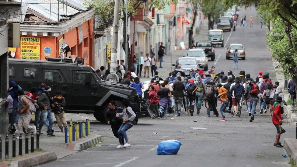 Demonstrators run away from an armoured vehicle during protests against fuel subsidy cuts