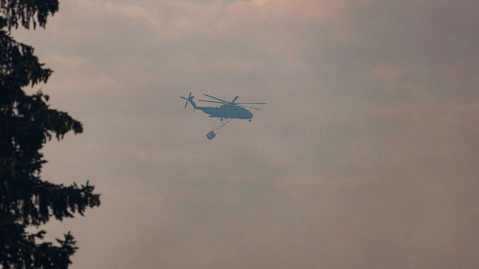 A helicopter carries water in order to extinguish a wildfire near Beelitz, southwest of Berlin.