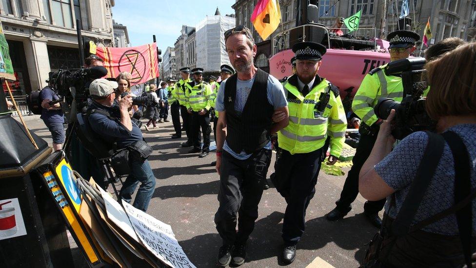 A protester being led off by a police officer in Oxford Circus