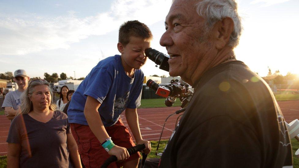 Ken Spencer (R) of Buckeye, Arizona, assists people as they look at the sun through a solar filter-equipped telescope at the Lowell Observatory Solar Eclipse Experience in Madras, Oregon, U.S.