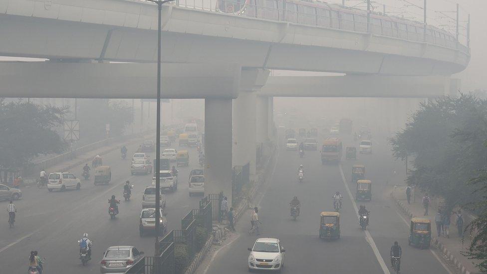 A Delhi Metro train (top) and vehicles drive past amid heavy smog in New Delhi on November 5, 2018