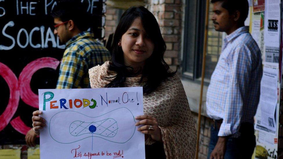 A woman holds a #HappyToBleed poster