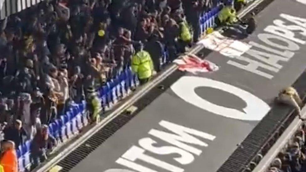 Man on edge of sloping roof above stand at Portman Road