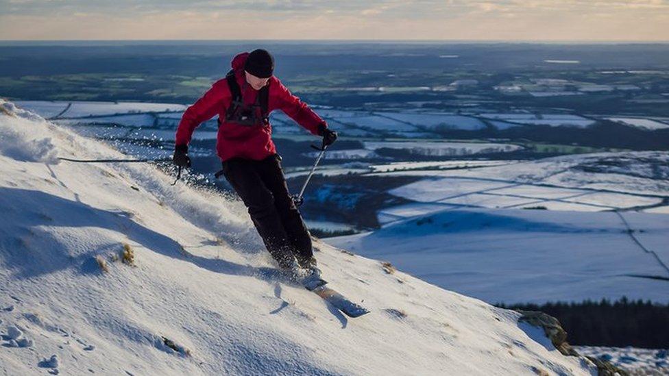 Chris Morris skiing on a hill above snow covered farmer's fields in the far back ground