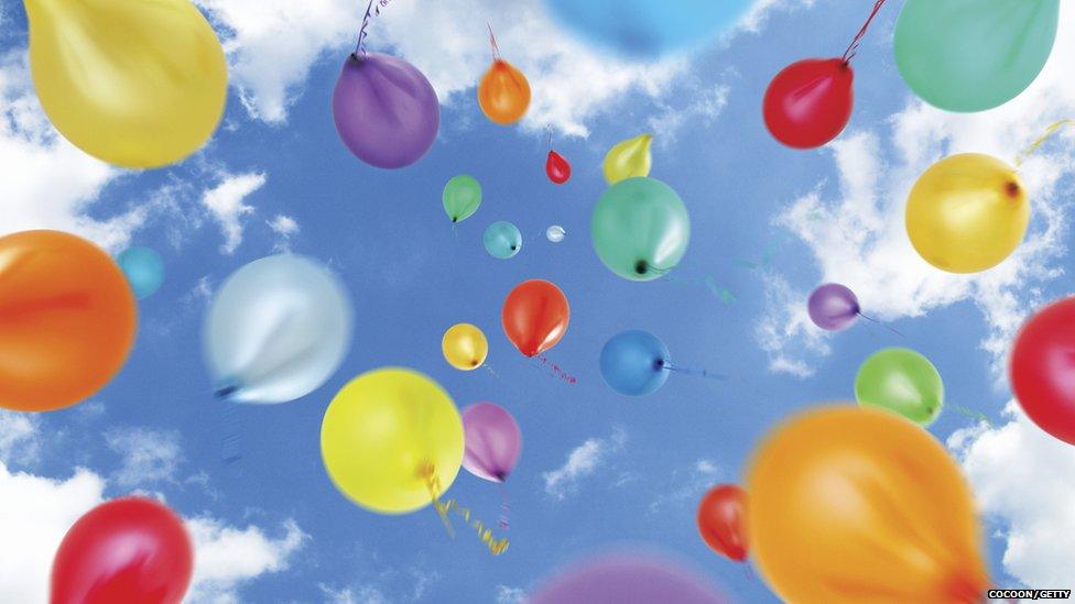 Balloons floating against a blue and slightly cloudy sky