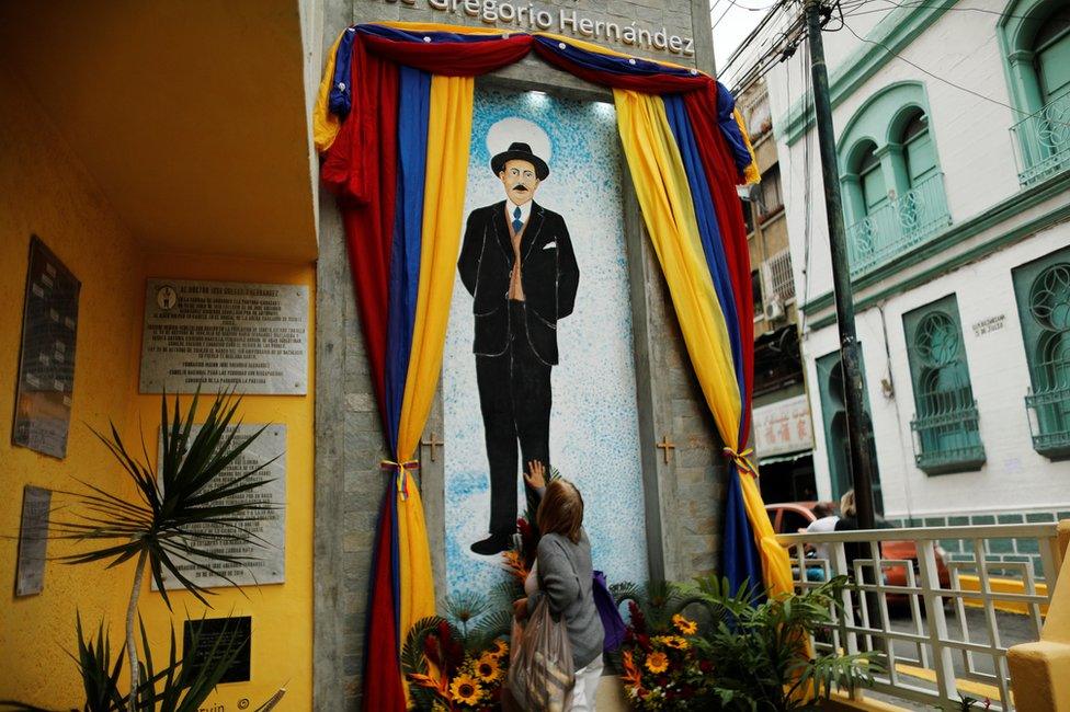 A woman places her hand on an image of Venezuelan doctor Jose Gregorio Hernandez