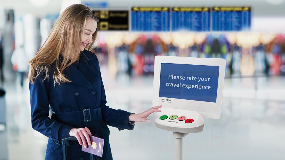 A woman using a Happy Or Not terminal at an airport