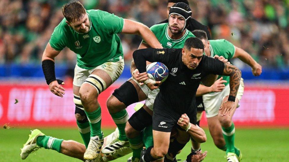 Irish rugby players tackle players from the New Zealand All-Blacks