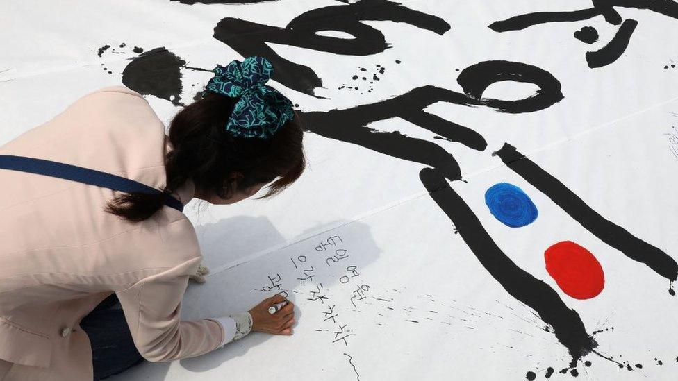 A South Korean woman writes goodwill messages during a rally to welcome the forthcoming Inter-Korean Summit