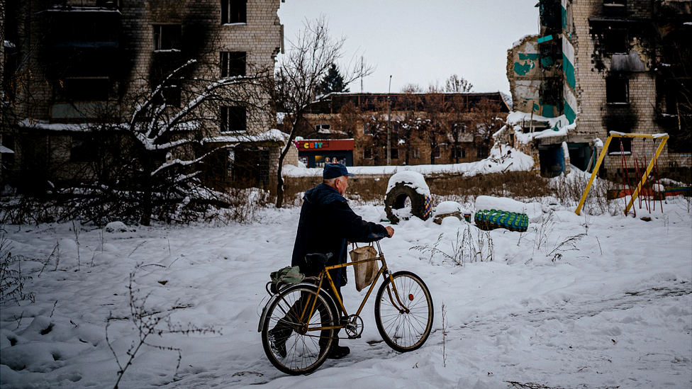 Man with bike on a snow covered street in Borodyanka, near Kyiv on 4 December