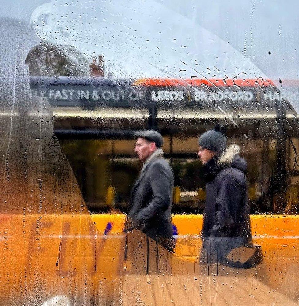 Image by Elaine Taylor of pedestrians passing a bus on Harrogate Road, Rawdon