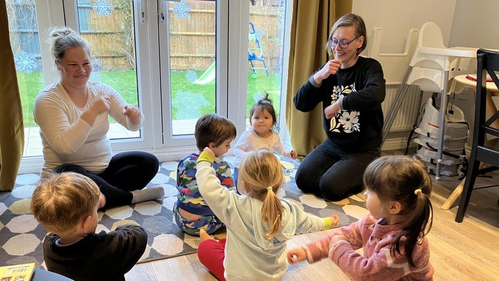 Childminder Hana Foltynova and her assistant singing a song with a group of children