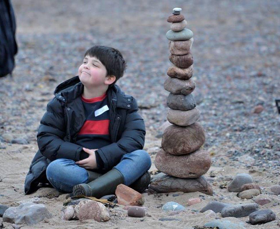 Boy with large stack of stones