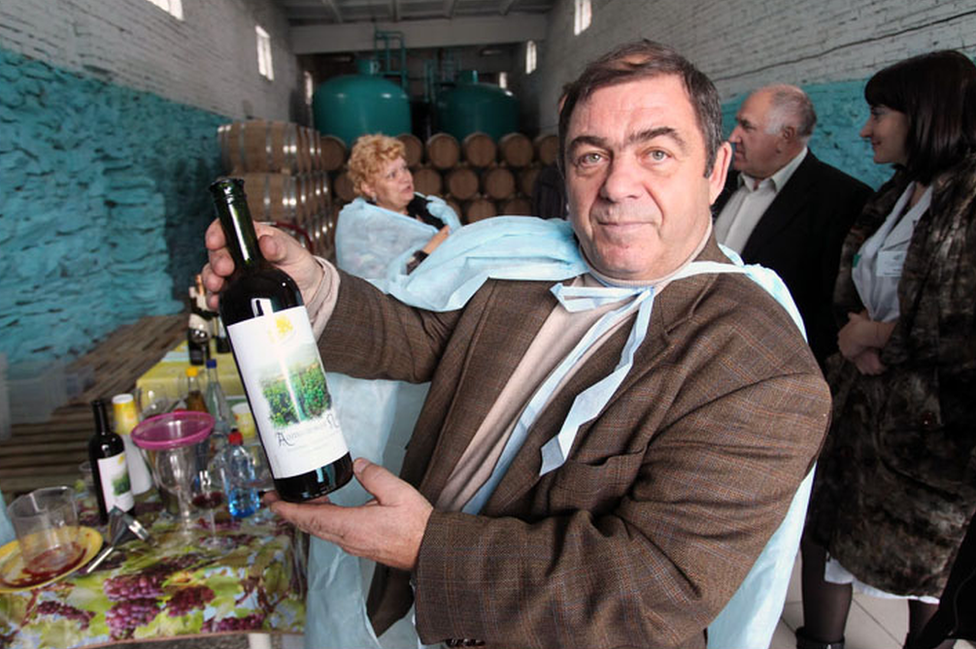 Vladimir Vagner is pictured holding a bottle of the vineyard's "Altai Vine" wine