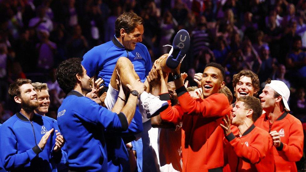 Roger Federer being lifted by other tennis players