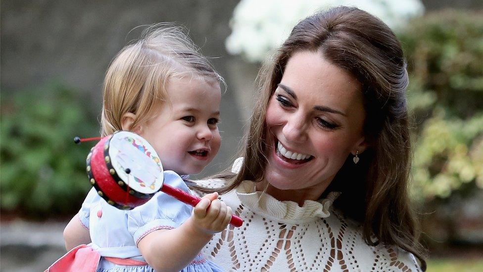 Princess Charlotte playing with a toy in Kate's arms