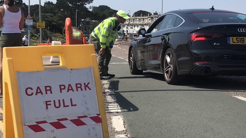 A car park marshal turning a driver away from a full car park