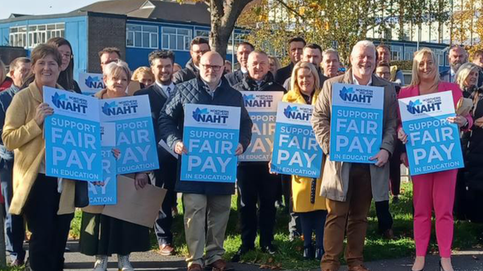 a line of people holding signs for NAHT, a headteachers' union