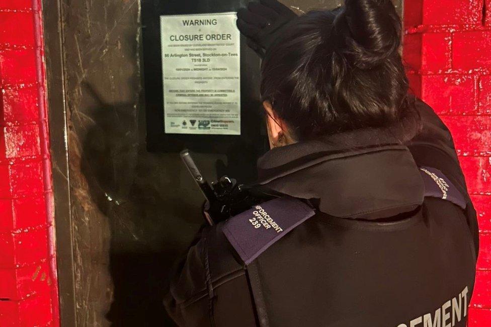 A female enforcement officer put a sign on a door