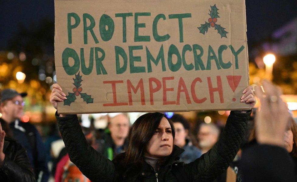 Protesters hold signs calling for the impeachment of US President Donald Trump outside the Los Angeles City Hall building, in Los Angeles, California on December 17, 2019.