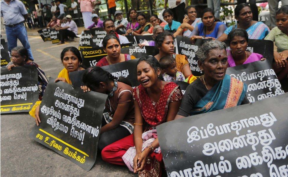 In this Wednesday, 14 October 2015 file photo, family members of ethnic Tamil detainees sit for a silent protest in Colombo, Sri Lanka. Sri Lanka's government has pledged to quickly process hundreds of ethnic Tamils who have been detained without charges for years on suspicion of links to former Tamil Tiger rebels. Placards read "Release all political prisoners now."