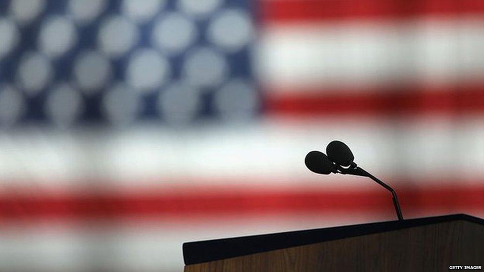 An empty microphone in front of a flag of the United States